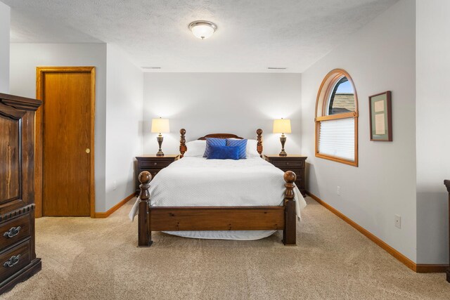 bedroom with light colored carpet and a textured ceiling