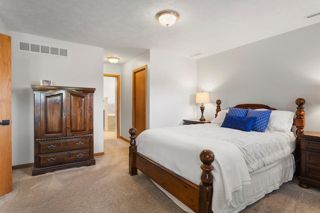 bedroom with a textured ceiling, connected bathroom, and light colored carpet