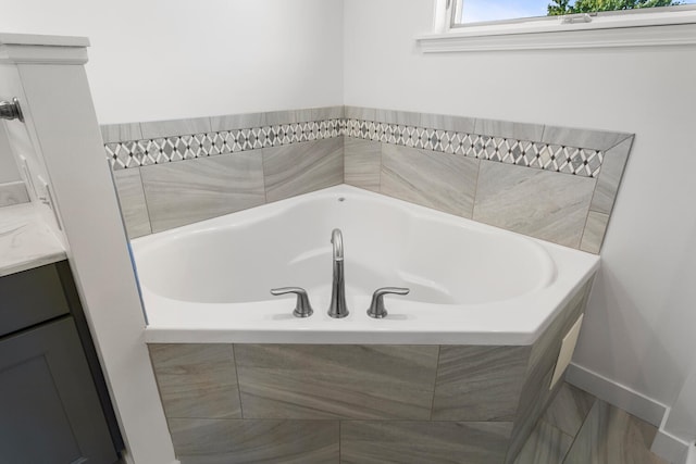 bathroom featuring tiled tub and vanity