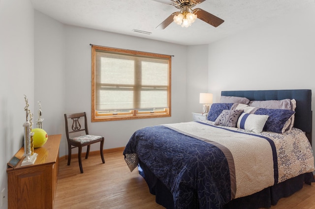 bedroom featuring ceiling fan, light hardwood / wood-style floors, and a textured ceiling