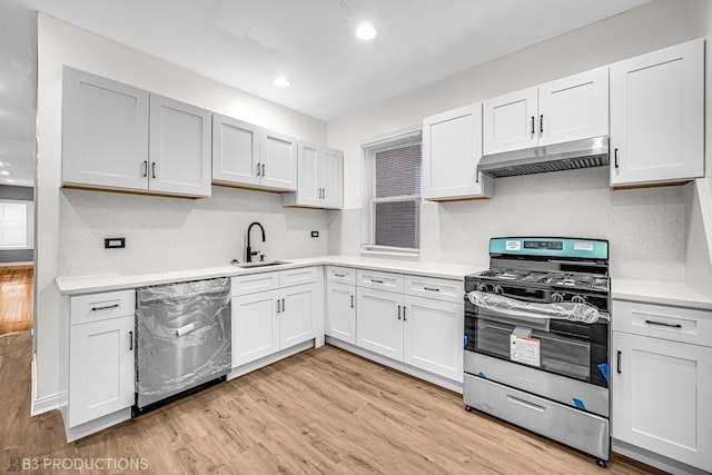 kitchen featuring sink, white cabinetry, appliances with stainless steel finishes, light hardwood / wood-style floors, and decorative backsplash