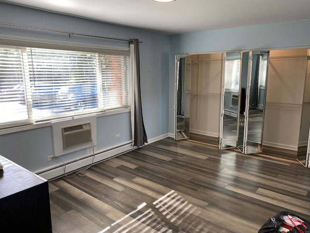 unfurnished bedroom with dark hardwood / wood-style floors, a wall mounted AC, and baseboard heating