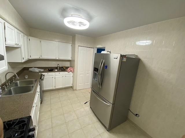 kitchen featuring stainless steel appliances, tile walls, sink, and white cabinetry