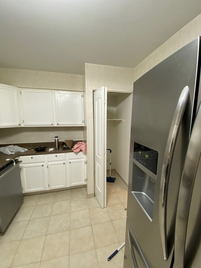 kitchen with appliances with stainless steel finishes, light tile patterned floors, and white cabinetry