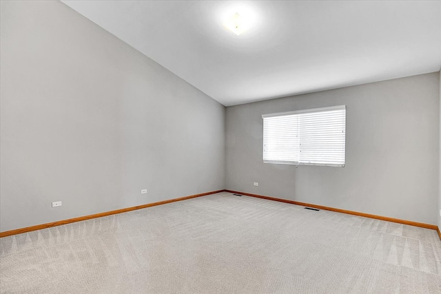 carpeted spare room with vaulted ceiling