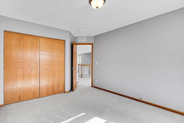 unfurnished bedroom featuring a closet and light colored carpet