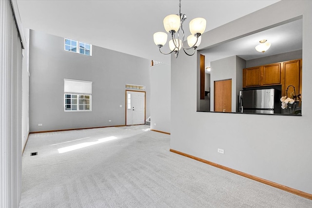 unfurnished living room featuring light carpet and an inviting chandelier