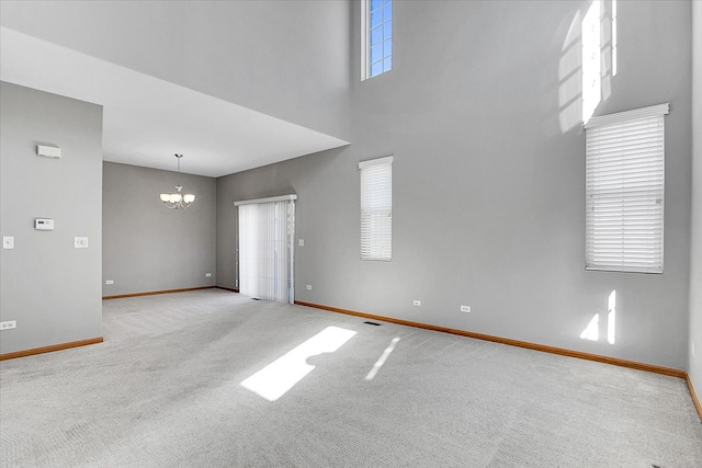 unfurnished room with a notable chandelier, a high ceiling, and light carpet