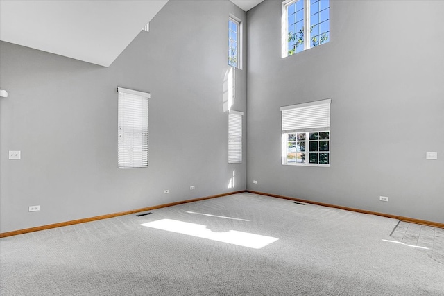 unfurnished living room featuring carpet and a high ceiling