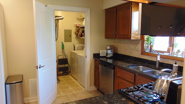 kitchen with tasteful backsplash, stainless steel dishwasher, independent washer and dryer, dark stone countertops, and sink