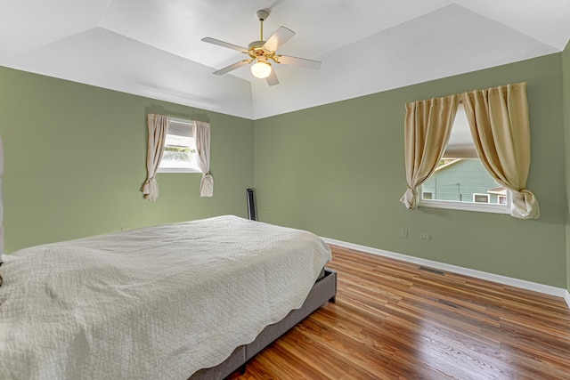 bedroom featuring lofted ceiling, baseboards, visible vents, ceiling fan, and wood finished floors