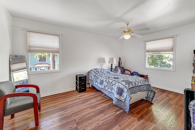 bedroom with ceiling fan, hardwood / wood-style flooring, and multiple windows