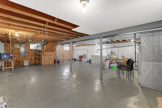 below grade area featuring stairway, wooden walls, electric panel, and washer and clothes dryer