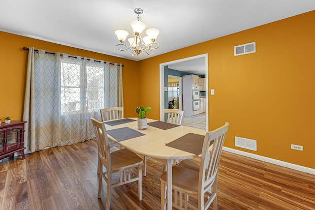 dining area with visible vents, an inviting chandelier, and wood finished floors