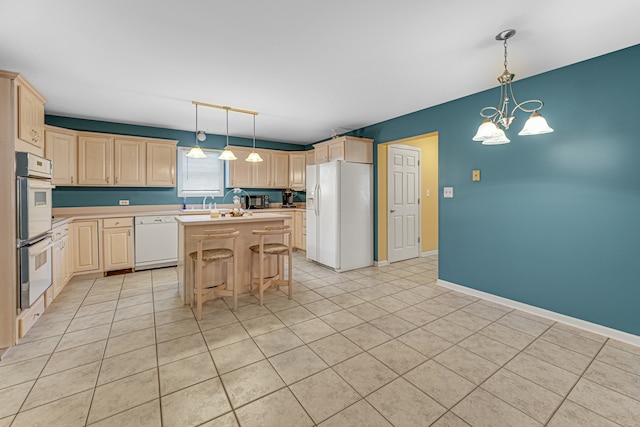 kitchen featuring light tile patterned flooring, white appliances, decorative light fixtures, a center island, and a notable chandelier