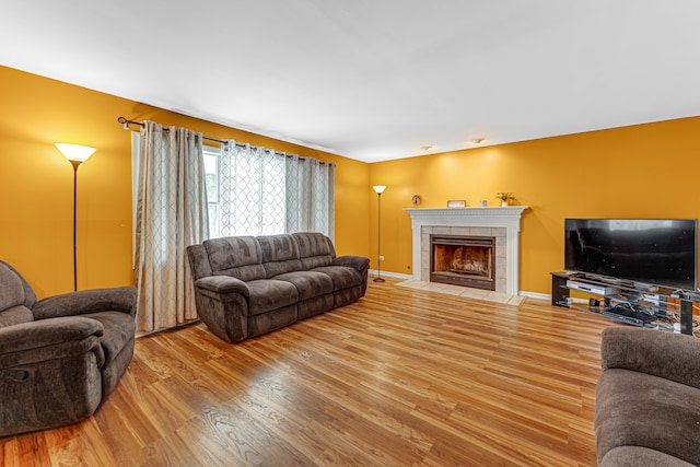 living room with wood-type flooring and a tile fireplace