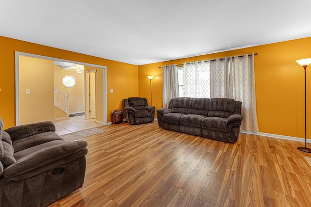 living room with baseboards, stairway, wood finished floors, and a healthy amount of sunlight