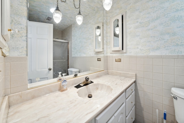 bathroom featuring vanity, an enclosed shower, tile walls, and toilet