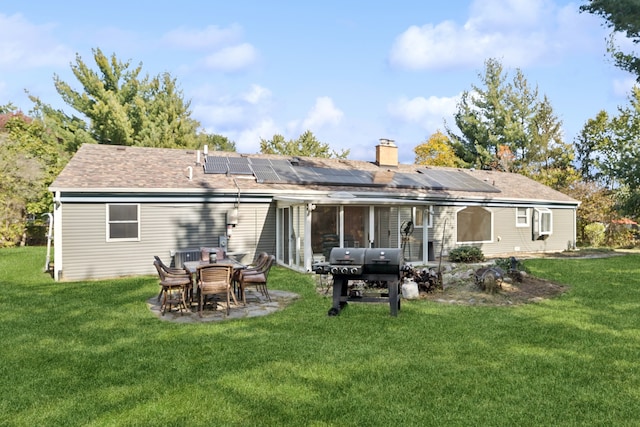 back of house featuring a lawn, solar panels, and a patio