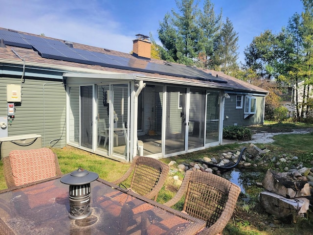 rear view of house featuring solar panels and a sunroom