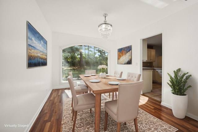 dining space with dark hardwood / wood-style floors and an inviting chandelier