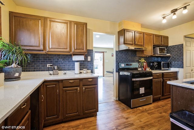 kitchen with backsplash, light stone countertops, stainless steel gas range, and dark wood-type flooring