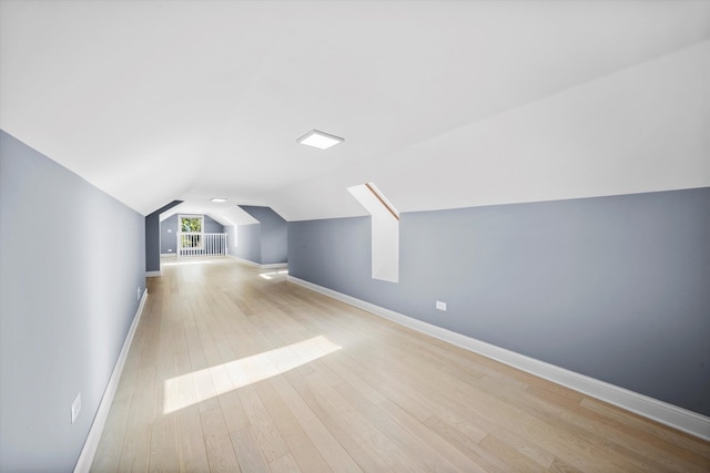 additional living space featuring light wood-type flooring and vaulted ceiling