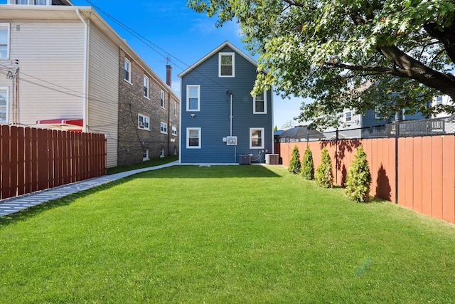 rear view of property featuring central air condition unit and a yard