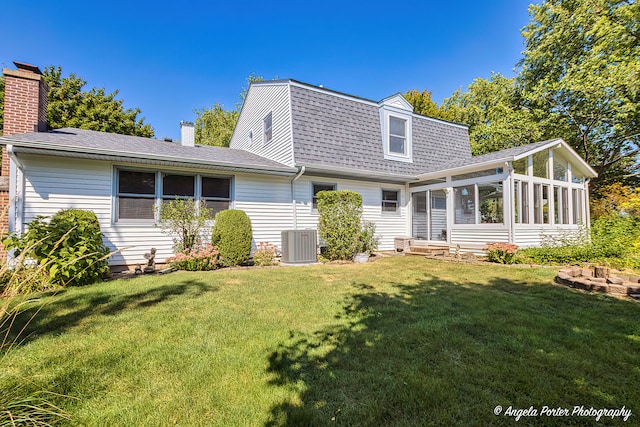 back of house featuring a sunroom, a yard, and central AC