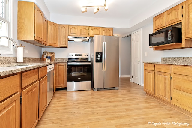 kitchen featuring light stone counters, sink, appliances with stainless steel finishes, and light hardwood / wood-style floors