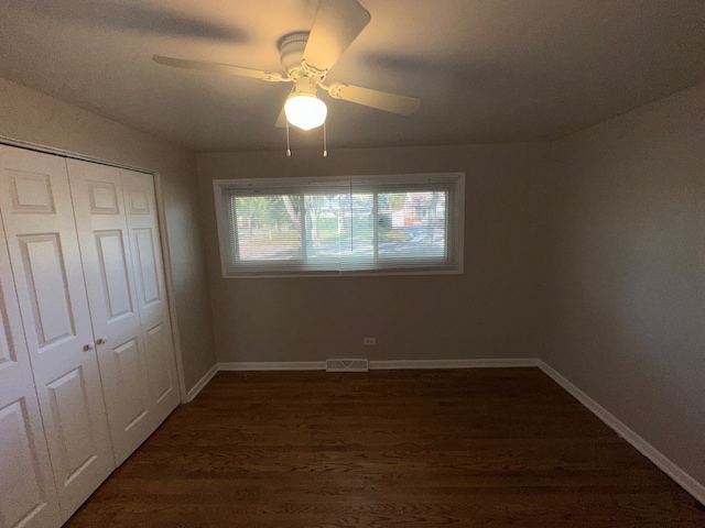 unfurnished bedroom featuring ceiling fan, a closet, and dark hardwood / wood-style flooring