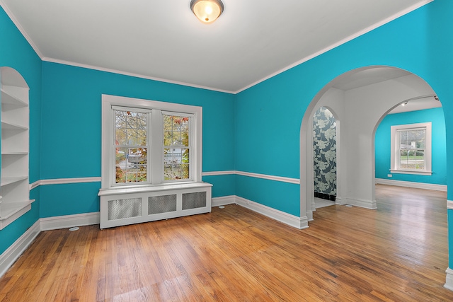 spare room featuring ornamental molding, hardwood / wood-style flooring, radiator, and a healthy amount of sunlight