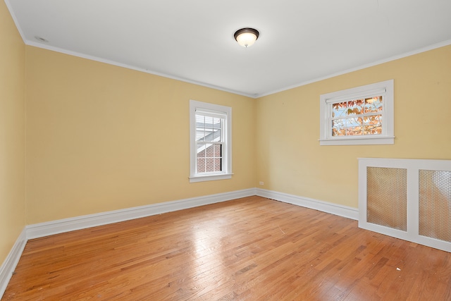 spare room featuring light hardwood / wood-style floors, ornamental molding, and radiator heating unit