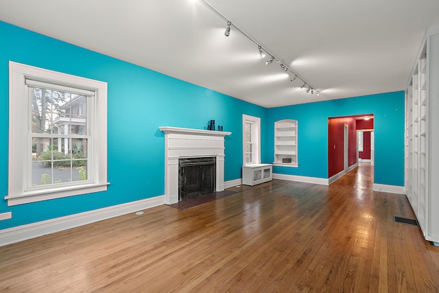 unfurnished living room featuring hardwood / wood-style flooring and track lighting