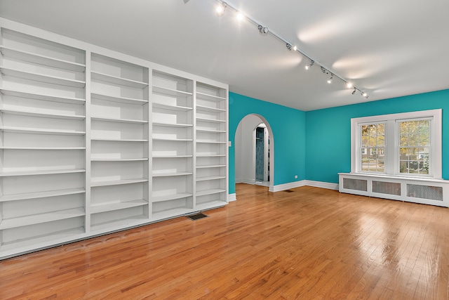 unfurnished living room with radiator, hardwood / wood-style floors, and rail lighting