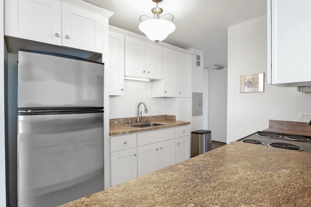 kitchen with range, sink, white cabinets, and stainless steel refrigerator