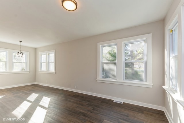 empty room featuring an inviting chandelier and dark hardwood / wood-style flooring