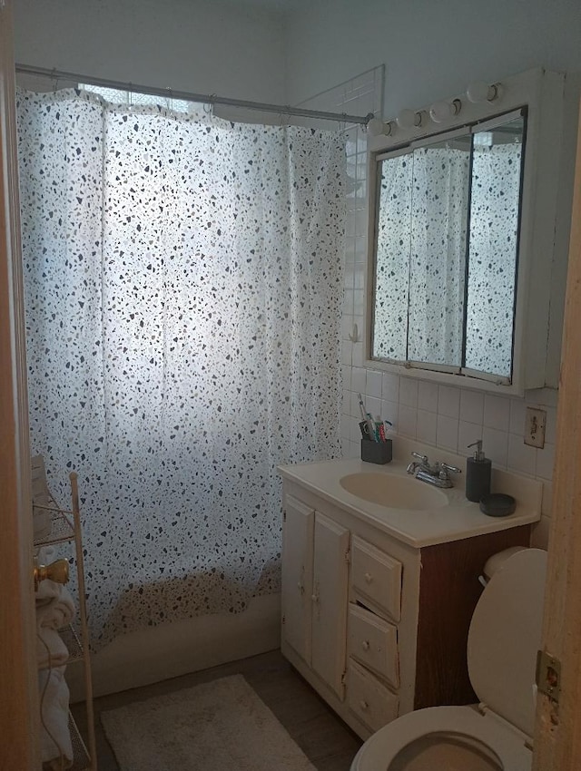 full bathroom with backsplash, vanity, shower / tub combo, and toilet