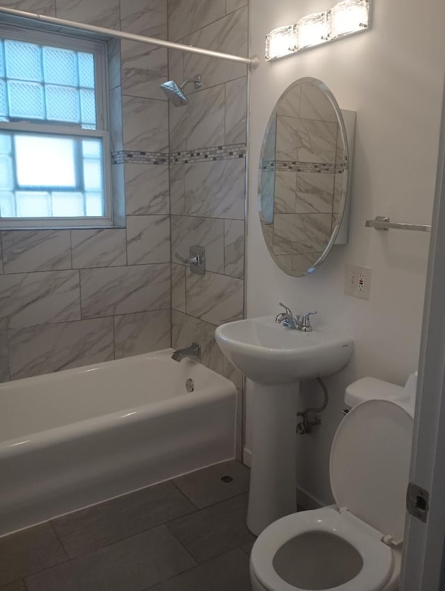 bathroom with tiled shower / bath combo, toilet, and tile patterned floors