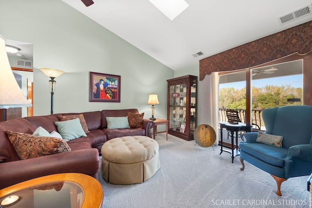 living room with light carpet, a skylight, high vaulted ceiling, and ceiling fan