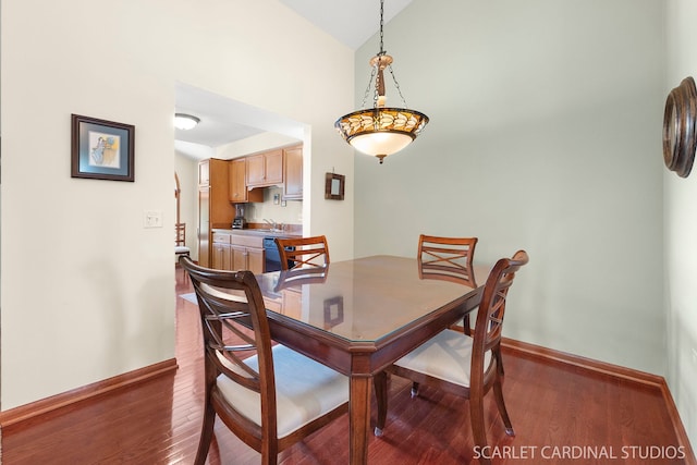 dining room with sink, wood-type flooring, and vaulted ceiling