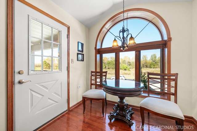 dining space with hardwood / wood-style floors, plenty of natural light, and an inviting chandelier