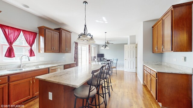 kitchen with a breakfast bar, ceiling fan, sink, pendant lighting, and a kitchen island