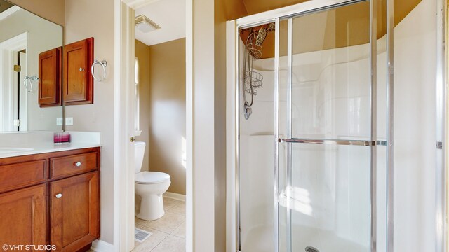 bathroom with toilet, vanity, tile patterned floors, and a shower with door