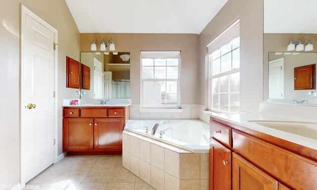 bathroom with tile patterned floors, a relaxing tiled tub, and vanity