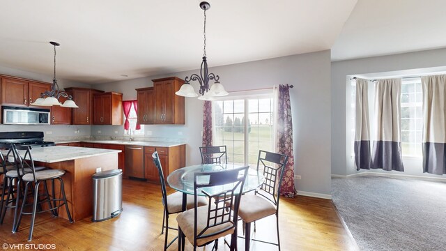 kitchen featuring sink, a center island, stainless steel appliances, an inviting chandelier, and decorative light fixtures