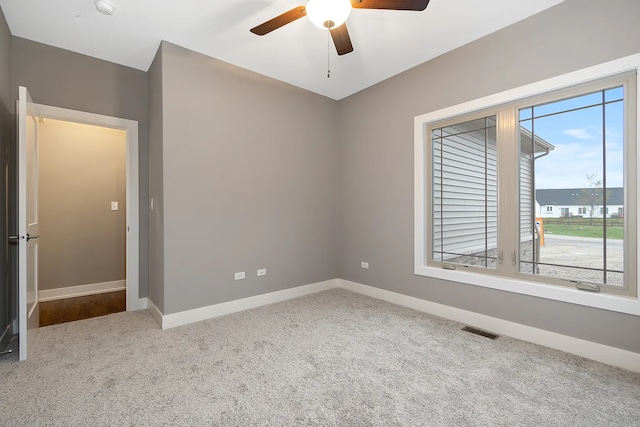 carpeted spare room with a healthy amount of sunlight and ceiling fan