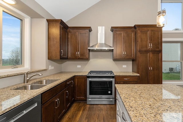 kitchen featuring stainless steel appliances, wall chimney range hood, sink, and a wealth of natural light