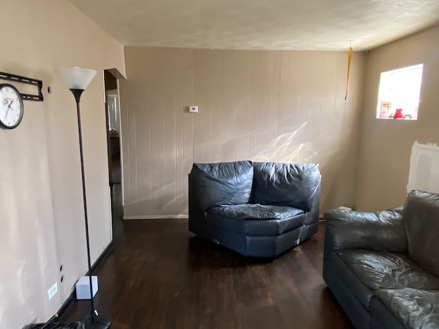 sitting room with wooden walls and dark wood-type flooring