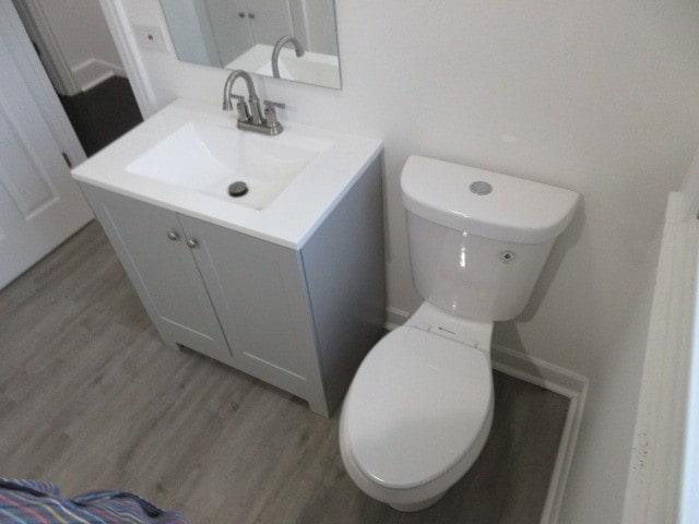 bathroom with toilet, vanity, and wood-type flooring